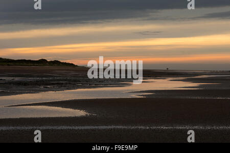 Lointain couple walking on Beach et dunes à Silloth-next-the-Sea, Norfolk, Angleterre Banque D'Images