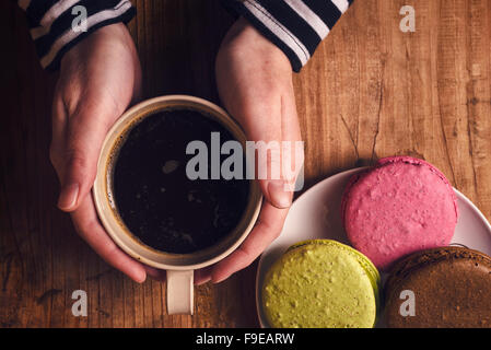 Café et biscuits macaron sur la table , femme hand holding cup avec boisson chaude, vue d'en haut, aux couleurs rétro Banque D'Images