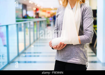 Belle femme avec bras cassé à l'intérieur d'un centre commercial Banque D'Images