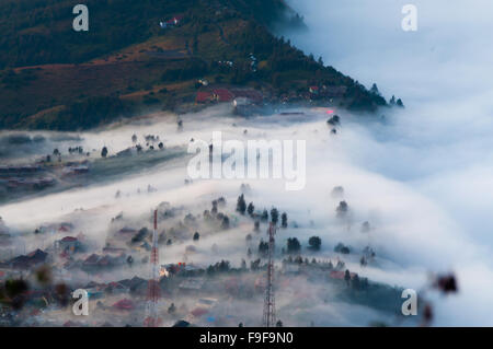 Couche de brume sur les montagnes et dans un village Banque D'Images