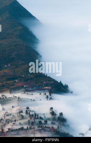 Couche de brume sur les montagnes et dans un village Banque D'Images