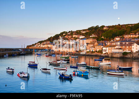 La première lumière de l'aube attraper les chalets le long du front de mer, surplombant le pittoresque port de Cornouailles de Mousehole. Banque D'Images