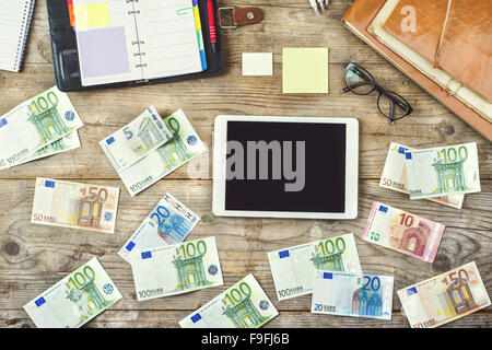 Mélange de fournitures de bureau, gadgets et de l'argent sur une table en bois. Vue de dessus. Banque D'Images