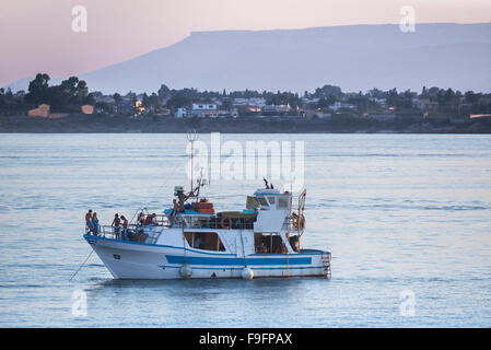 Bateau jeunes Méditerranée, vue au crépuscule des jeunes socialisant sur un grand bateau dans le port de Syracuse (Syracuse) Sicile, Italie Banque D'Images