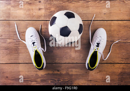 Chaussures de foot et ballon posé sur un sol en bois historique Banque D'Images