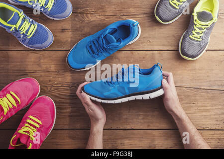 Homme tenant une paire de chaussures de course de fond sur un sol en bois Banque D'Images