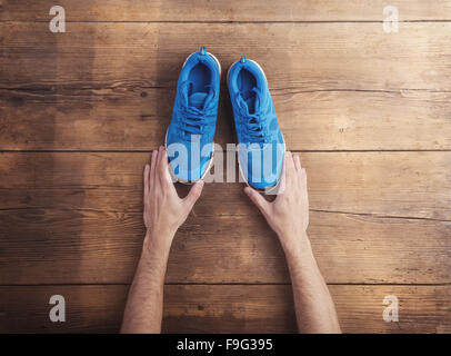 Homme tenant une paire de chaussures de course de fond sur un sol en bois Banque D'Images