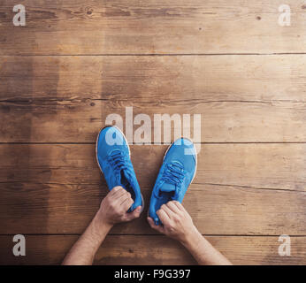 Homme tenant une paire de chaussures de course de fond sur un sol en bois Banque D'Images