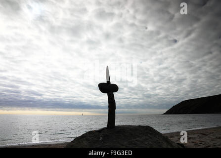 Une croix de pierre sur une plage avec un ciel nuageux et de pointe. Banque D'Images