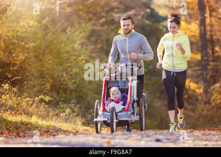 Beau jeune famille avec bébé en poussette fonctionne en dehors de la nature en automne Banque D'Images