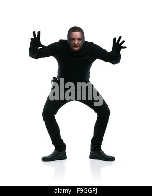 Voleur en action avec passe-montagne sur son visage, vêtus de noir. Studio shot sur fond blanc. Banque D'Images