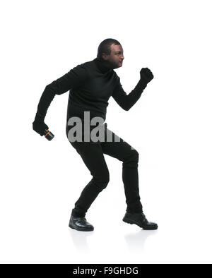 Voleur en action avec passe-montagne sur son visage, vêtus de noir. Studio shot sur fond blanc. Banque D'Images