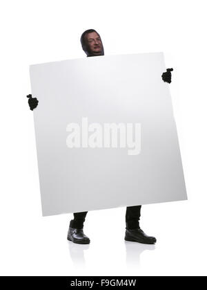 Voleur avec passe-montagne sur son visage, vêtus de noir, tenant une bannière vide. Studio shot sur fond blanc. Banque D'Images