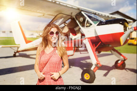 Belle femme en robe d'été debout devant des petits avions d'époque. Banque D'Images