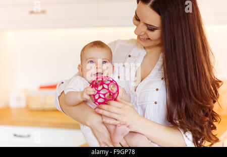 Cute little baby girl jouant avec sa mère dans un salon. Banque D'Images