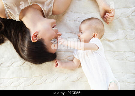 Cute little baby girl et sa mère allongé sur une couverture en tricot. Banque D'Images