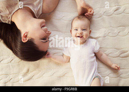 Cute little baby girl et sa mère allongé sur une couverture en tricot. Banque D'Images
