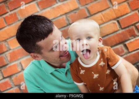 Père et fils faire des grimaces ensemble sur un mur de briques historique Banque D'Images
