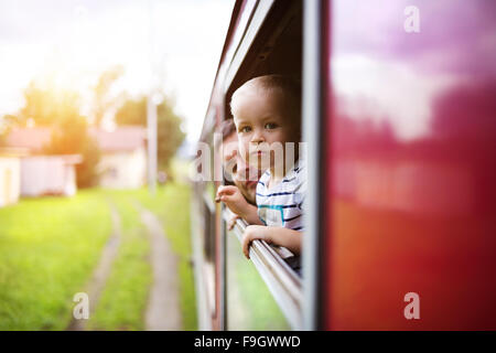 Petit garçon voyageant en train à l'extérieur de la fenêtre. Banque D'Images