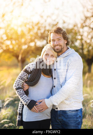 Happy young pregnant couple de passer du temps ensemble à l'extérieur dans la nature verte. Banque D'Images