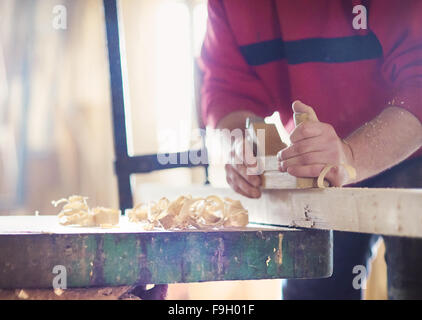 Menuisier travaillant avec planer sur planche en bois à l'atelier Banque D'Images
