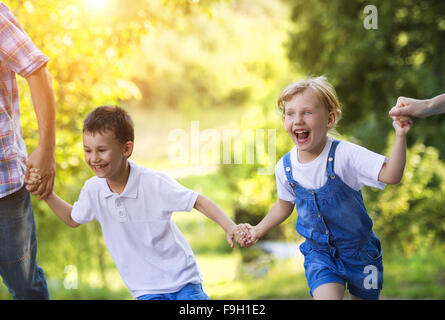 Happy little girl and boy s'amusant avec leurs parents dans la nature verte. Banque D'Images