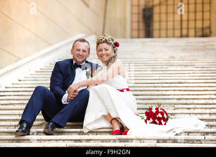 Beau couple de mariés à l'extérieur du château sur les escaliers Banque D'Images