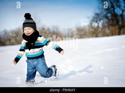 enfant en hiver. un petit garçon dans un chapeau chaud et des mitaines  regarde la caméra et sourit. 18907117 Photo de stock chez Vecteezy