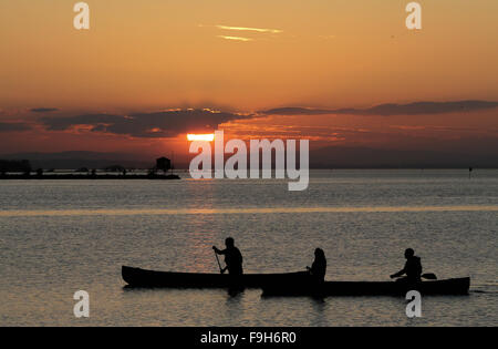 Trois personnes kayak au coucher du soleil sur un lac d'eau douce - Kinnego près de Oxford Island sur le Lough Neagh en Irlande du Nord. Banque D'Images