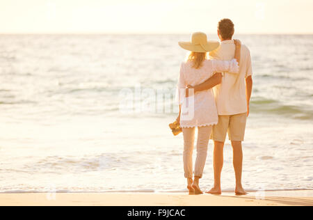 Happy Romantic Couple d'âge moyen avec sa promenade sur la plage au coucher du soleil. Voyage Vacances Concept de vie à la retraite Banque D'Images