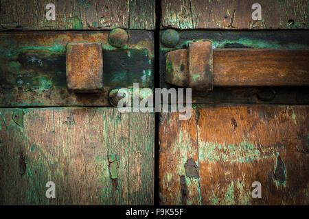 Extreme close-up d'un loquet rouillé, monté sur une vieille porte en bois avec de la peinture. Banque D'Images