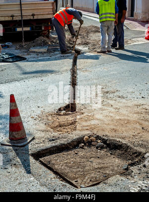 Les travailleurs pendant la construction du réseau à large bande avec de la fibre de verre dans une rue de la ville Banque D'Images