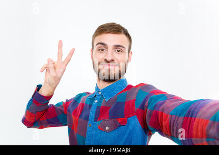 Photo de selfies beau jeune homme positif chemise à carreaux en montrant la victoire Banque D'Images