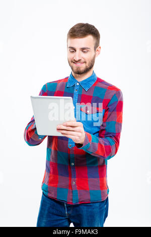 Contenu smiling attractive jeune homme en chemise à carreaux using tablet computer Banque D'Images