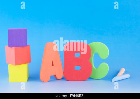 Lettres ABC cubes de mousse colorée, et des craies sur fond bleu Banque D'Images