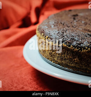 Gâteau au chocolat noir sur plaque blanche avec fond rouge Banque D'Images