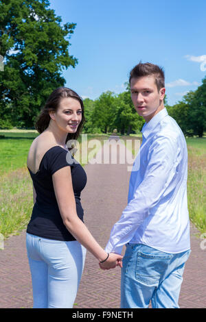 Young attractive caucasian man and woman marche main dans la main à l'arrière Banque D'Images