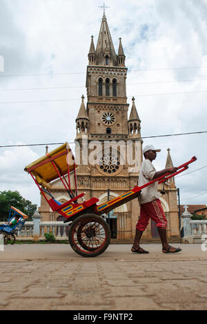 Un Pous Pous conducteur par la cathédrale dans le centre d'Antsirabe à Madagascar. Banque D'Images