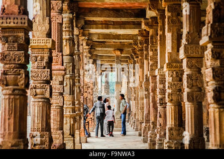 Visiteurs de la mosquée Quwwat ul-Islam, photographiés dans une ruelle décorée de colonnes sculptées au complexe Qutab Minar à Mehrauli, Delhi, Inde. Banque D'Images