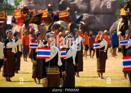 Danseuses en costume traditionnel rural thaïlandais portent drapeaux au cours de l'extérieur à l'assemblée annuelle de l'éléphant le Roundup Surin Banque D'Images