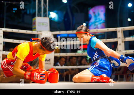 Deux femmes combattants de muay thai à genoux côte à côte, en s'inclinant, effectuant le kickboxing danse rituelle appelée le wai khru avant match Banque D'Images