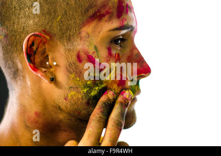 Vue de côté de l'homme visage peint avec l'application de poudres de couleurs de Holi. Isolé sur fond blanc. Close-up. Banque D'Images