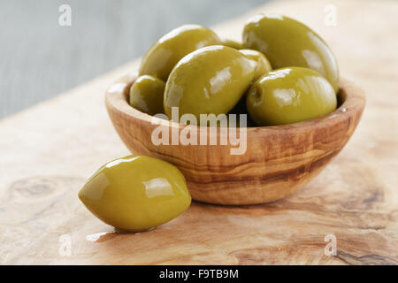 Olives vertes géantes dans bol d'olive sur fond de bois Banque D'Images