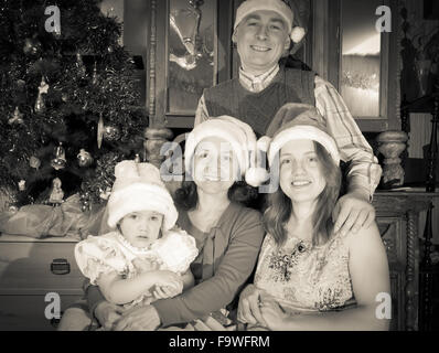 Imitation de vintage photo de famille heureuse de trois générations qui pose pour portrait de Noël Banque D'Images