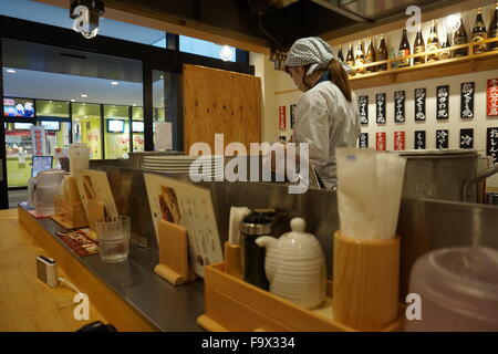 Une femme cuisiner les nouilles dans un bar pour le déjeuner à Tokyo, Japon Banque D'Images