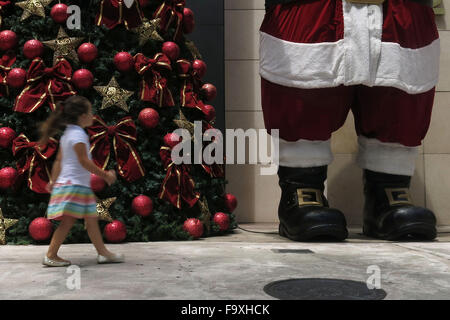 Sao Paulo. Le 15 décembre, 2015. Image prise le 15 décembre 2015 montre une fille qui marche en avant d'une figure du Père Noël au centre commercial à Sao Paulo, Brésil. En Amérique latine, une région où le catholicisme prédomine, Noël dans l'une des principales célébrations. © Rahel Patrasso/Xinhua/Alamy Live News Banque D'Images