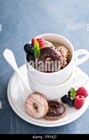 Petit vitrage mini donuts empilés dans des tasses à café Banque D'Images