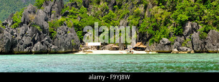 Île rocheuse avec des huttes de Nipa maisons sur une plage de sable blanc solitaire Banque D'Images