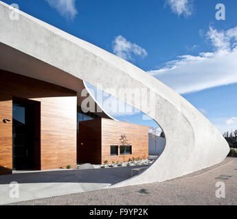 Une structure extérieure incurvée blanc dramatique autour d'un bâtiment qui offre des espaces sociaux et de traitement pour les patients atteints de cancer, dans le parc d'un hôpital. Les soins de santé. Banque D'Images