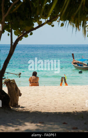 Tourist femme assise sur le sable blanc en face de calme bleu turquoise de la mer en regardant l'océan avec la plongée palmes sur sunny, claire Banque D'Images